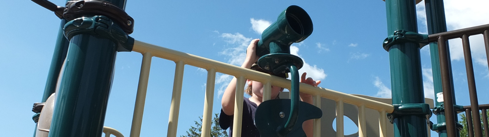 Child looking through telescope on the PMA playground