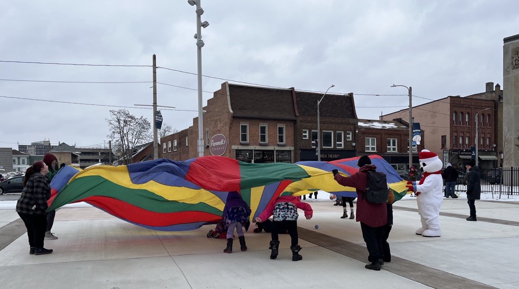 Snofest Pete and community members play with a giant parachute during a Snofest event