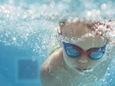 Child swimming underwater with goggles